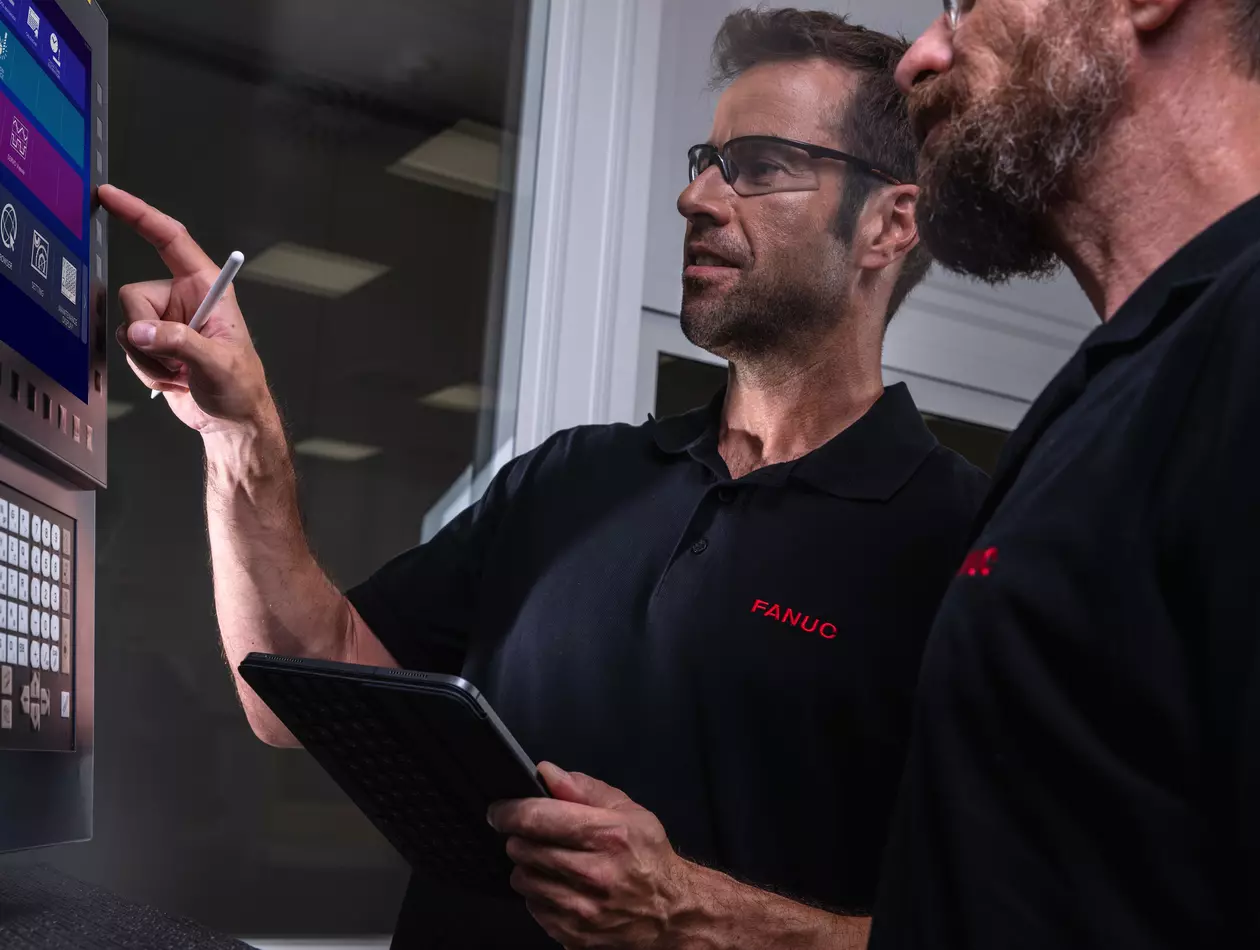 Service / maintenance photo with person. Two men at a machine control panel. Landscape. High resolution.