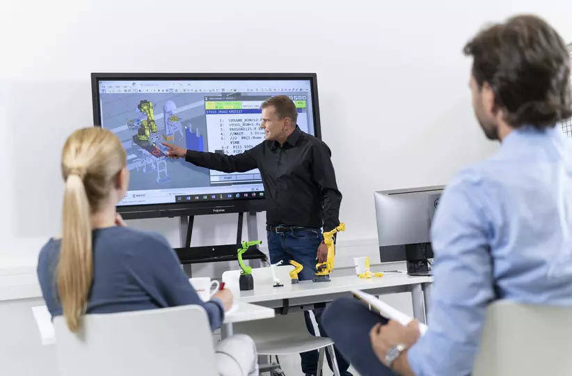 Image showing FANUC Academy trainer explaining two partipants the ROBOGUIDE Handling Pro software.