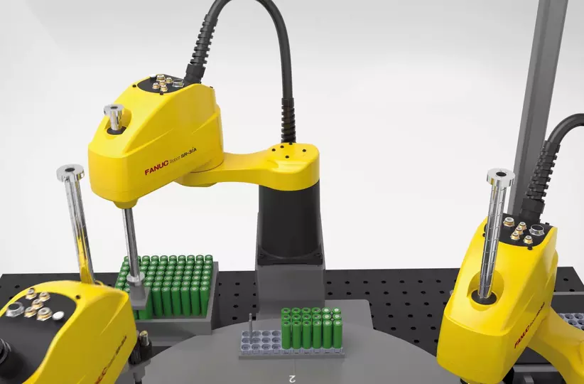 The FANUC SR-3iA robot is picking and placing batteries.