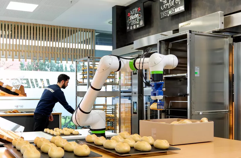 Success story about successful implementation of a FANUC cobot  at the company WIESHEU (food industry). FANUC collaborative robot  CRX-10iA/L takes the buns from a crate, sorts them onto a baking tray and pushes the trays into shelves for baking. The CRX also tips the baked rolls from the tray into sales racks.