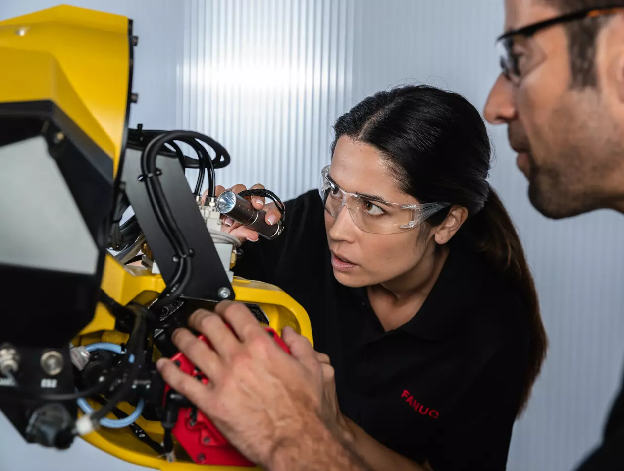 Service / maintenance photo with person. Woman and man. Intervention at a robot. Landscape. High resolution.