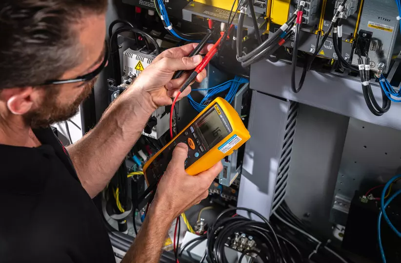 Service / maintenance photo with person. Man on the left working at the control cabinet. Landscape. High resolution.