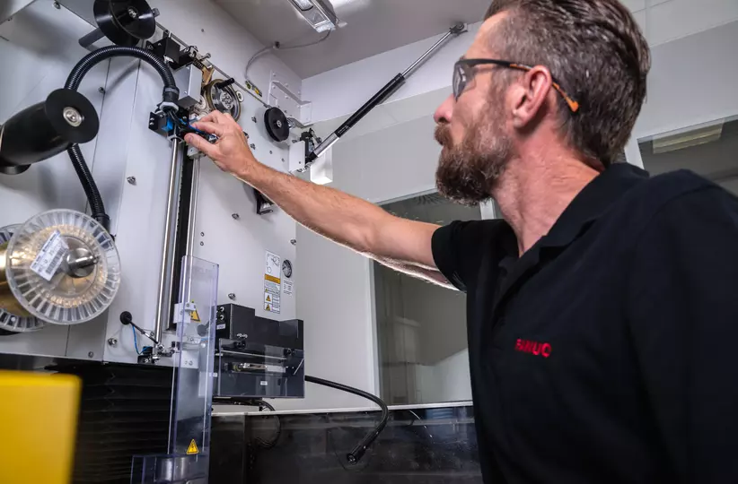 Service / maintenance photo with person. Man on the right. Intervention at a ROBOCUT. Landscape. High resolution.