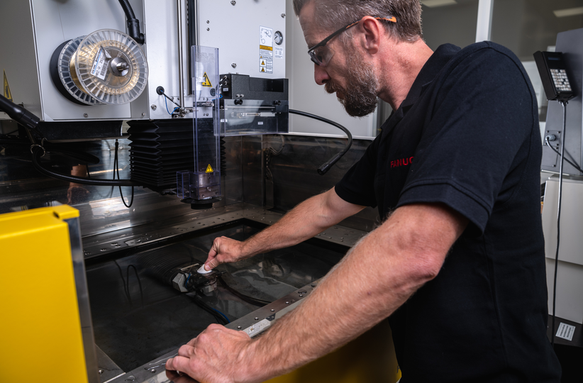 Service / maintenance photo with person. Man on the right. Intervention at a ROBOCUT. Landscape. High resolution.