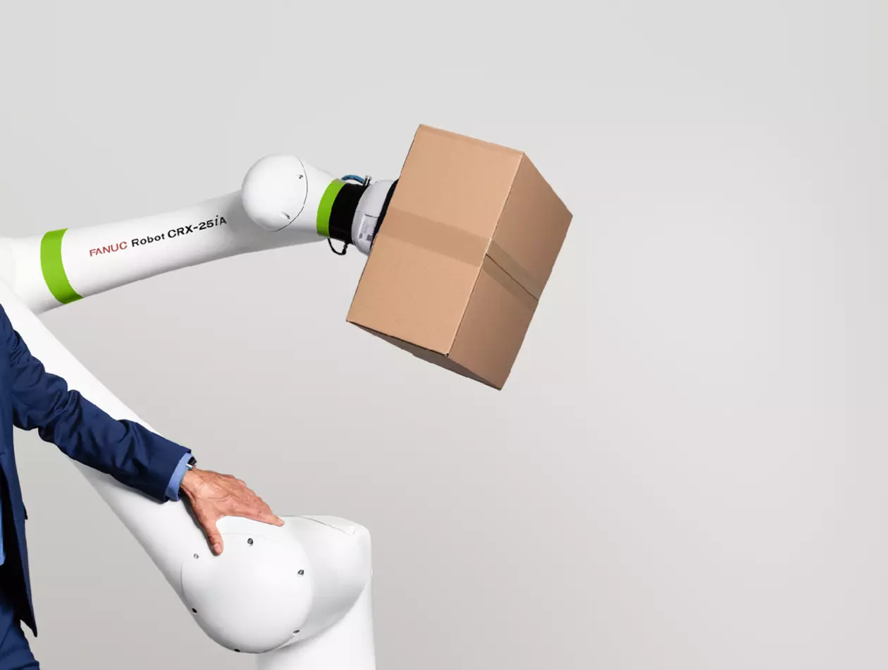 Image of C-level man standing next of a CRX-25iA robot handling a cartoon box.