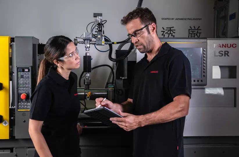 Service / maintenance photo with person. Woman and man in front of a ROBOSHOT LSR. Landscape. High resolution.