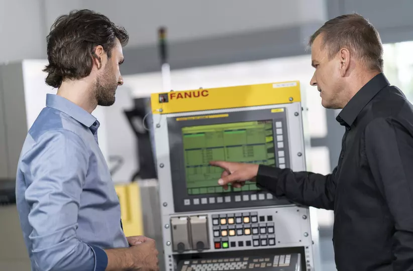 Customer at training with FANUC employee in front of controls.