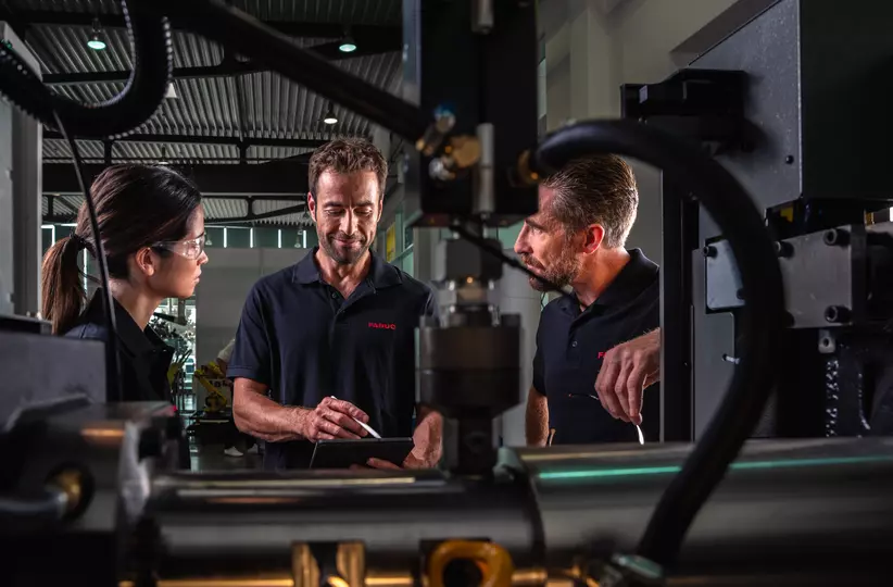 Service / maintenance photo with person. Woman and two men. View through the inside of a machine. Landscape. High resolution.