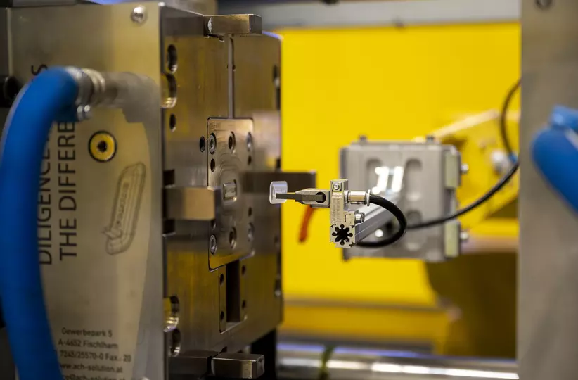 Virtual show 2021. Detail image of plastic workpiece being picked by a robot.