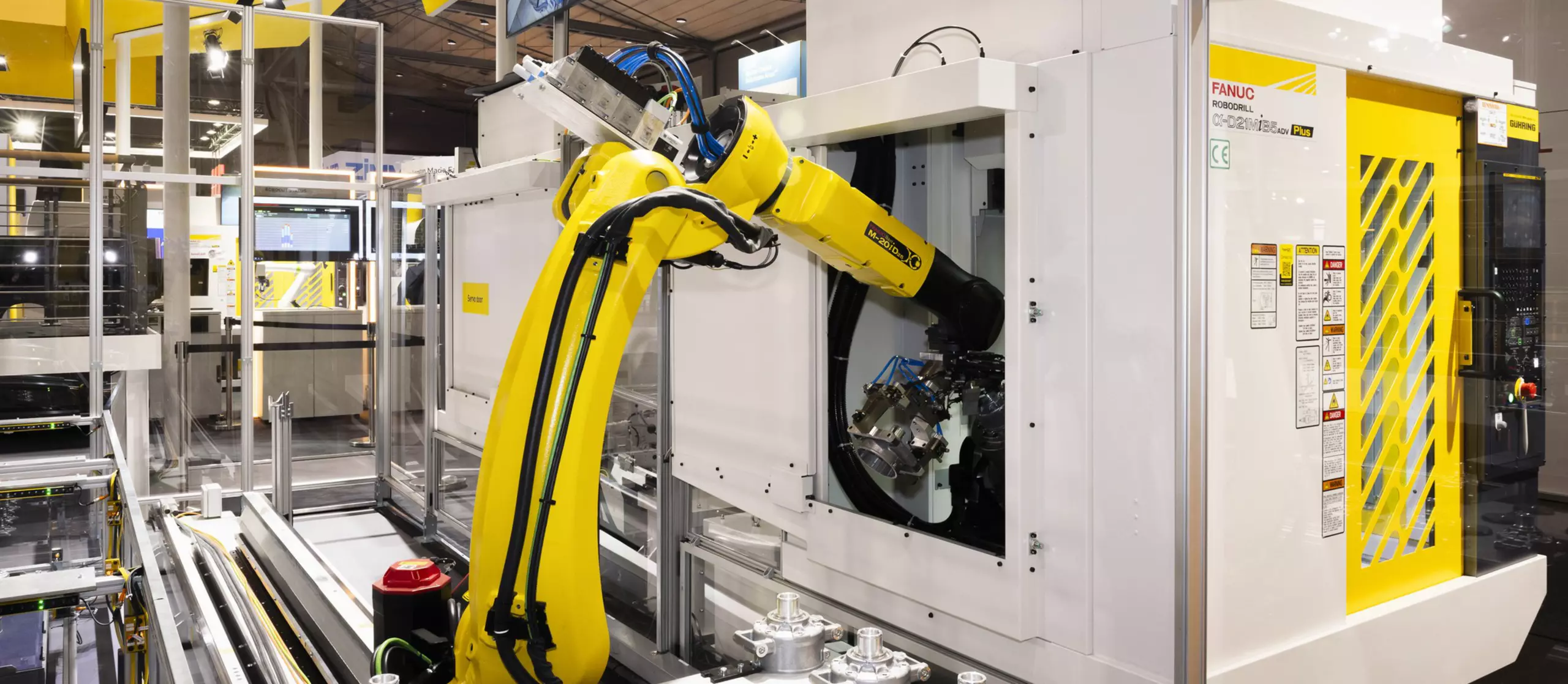 Machine tending with FANUC Robot. FANUC M-20iD/25 loading/unloading FANUC Robodrill D21MiB5 Plus machining center. The time required for the servo door to open and close has been significantly reduced when compared to traditional air cylinder operations. Fully automated production line at EMO 2023. 