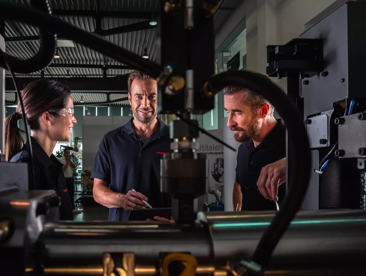 Service / maintenance photo with person. Woman and two men. View through the inside of a machine. Landscape. High resolution.